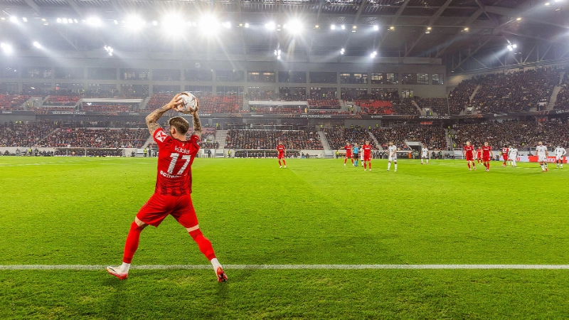 Der SC-Freiburg Spieler Kübler im roten Trikot macht einen Einwurf von der Seitenlinie.
