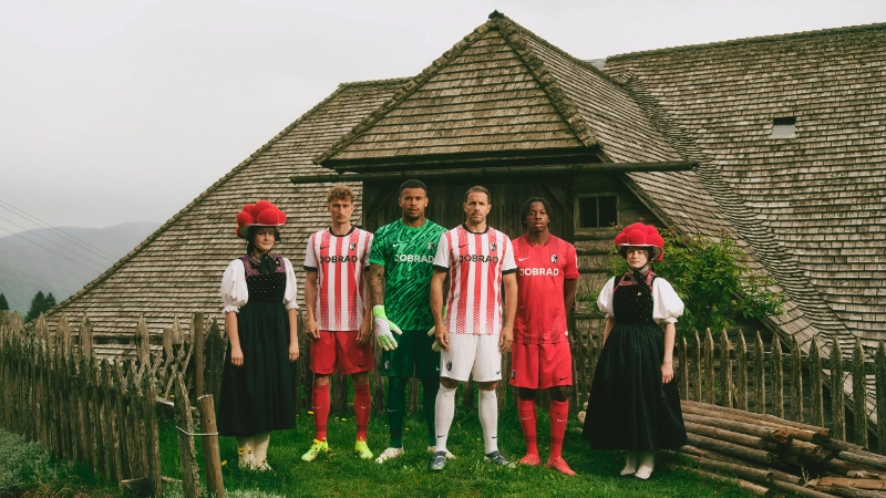 4 SC-Spieler stehen mit 2 Schwarzwaldmädeln bei Nebel vor der Tenne und schauen ernst 4 SC-Spieler stehen mit 2 Schwarzwaldmädeln bei Nebel vor der Tenne und schauen ernst